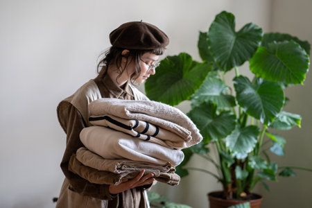 Conscious teen girl holding stack of old organic cotton clothes for donation, recycling, reuseの写真素材