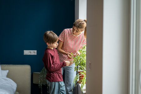 Young mother teaching kid son how to care for houseplantsの写真素材