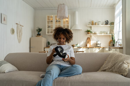 Excited African American woman looking at her first VR headset and feeling excited to get immersedの写真素材