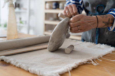 Potter sculptor cutting clay with the string in workshop for sale in retail storeの写真素材