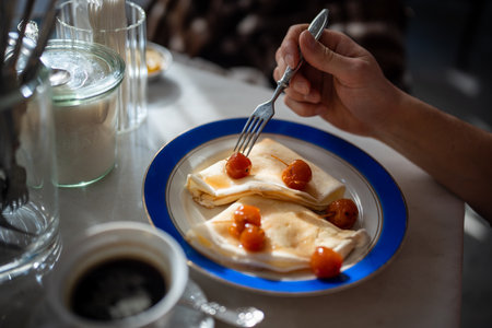 Man having tasty breakfast in restaurant pancakes with jam from apples ranets.の写真素材
