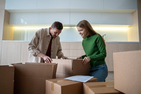 Merry happy homeowners unpacking carton boxes in new flat. Relocation day into purchased apartment
