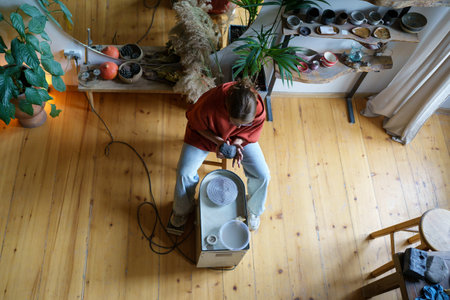 Immersive in process girl sculptor using clay to create new clay products sitting near potter wheel