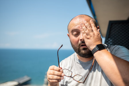 Bald fat man drenched in sweat wiped off excess moisture. Sweating, high temperature, overweightの写真素材