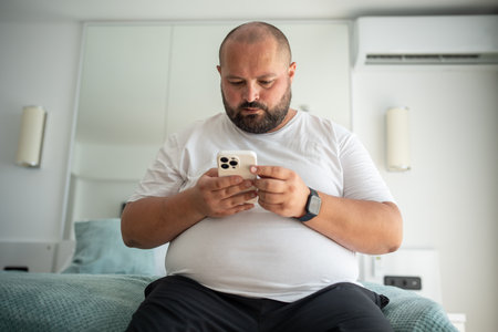 Fat bearded bald guy with smartphone chatting, dials number, types message, watches news, weather