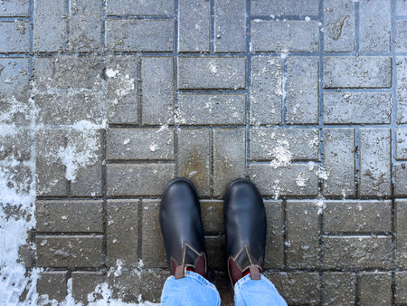 Winter boots on road with rock salt, top view. Chemical reagents to melt ice, prevent icing