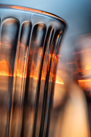Closeup of wine glass, faceted tumbler, goblet, shot glass for drinks illuminated by orange light.の写真素材