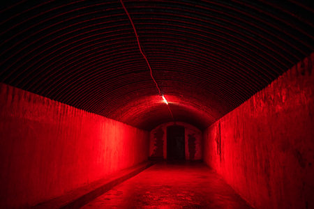 Red light corridor inside underground old bunker. Tunnel illuminated with bright red neon lights.の写真素材
