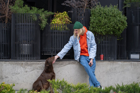 Kind stylish hipster guy in trendy outfit caressing dog, playing, amusing petの写真素材