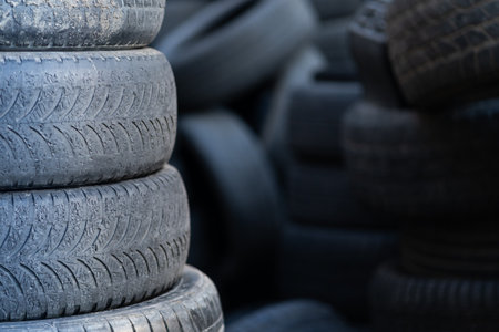 Old used rubber tires stacked with high piles. Hazardous waste requiring recycling and disposal.