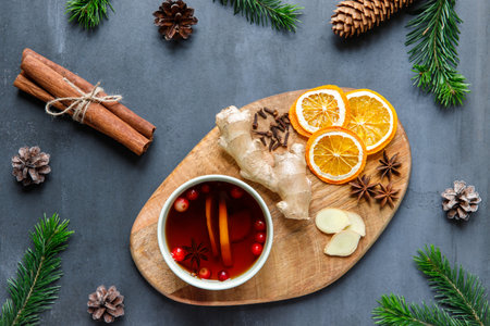 Flat lay of mug of hot tea with lemon, cranberries, cloves, anise, ginger. Natural remedies for...