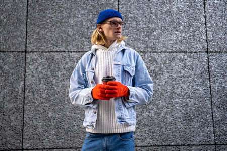 Trendy stylish guy waiting outdoors with take away coffee