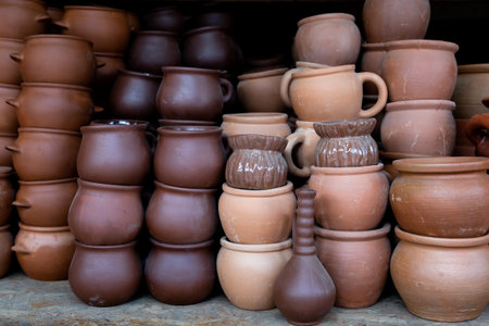 Stocks of various terracotta and brown pots for plants or cooking for sale on counter at shop.