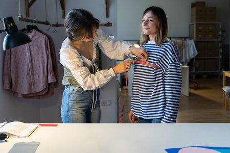 Fashion designer woman takes measurements with measuring tape of client before tailoring clothes