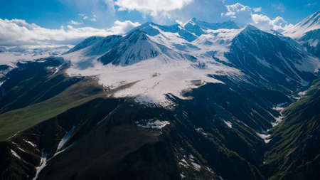 Aerial view of beautiful mountainous range and valley in Georgia. Mountains with snowy tops, blue skyの写真素材