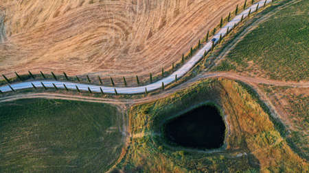 Abstract nature landscapes from drone, Tuscany, Italy. Road with cypress trees and pond.の写真素材
