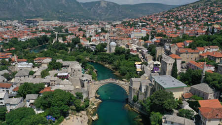 Aerial view of Stari Most old medieval bridge in Mostar, Neretva river, Bosnia and Herzegovina. Tourists walking on the bridge. Summer landscape of old town. Mosque on background.のeditorial素材