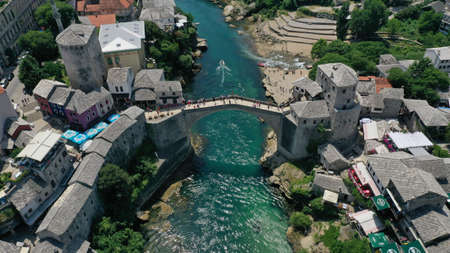 Aerial view of Stari Most old medieval bridge in Mostar, Neretva river, Bosnia and Herzegovina. Tourists walking on the bridge. Summer landscape of old town. Mosque on background.のeditorial素材