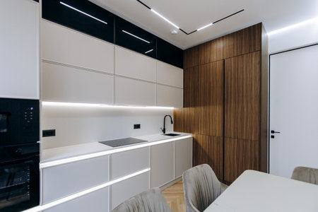 A kitchen with white cabinets, wooden walls, table, and chairsの写真素材