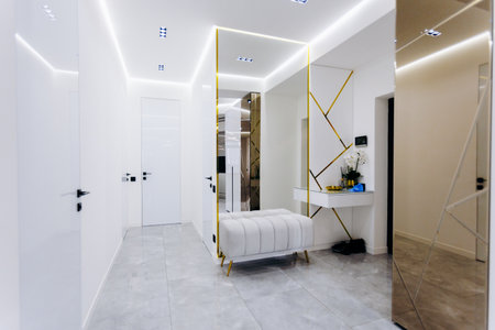 A hallway that features a bench and a mirror mounted on the wallの写真素材