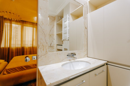 The bathroom features a functional sink along with a spacious mirrorの写真素材