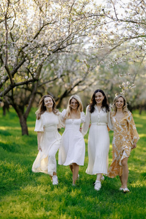 Women in elegant white dresses are happily walking in a parkの写真素材