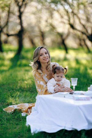 A woman sits at a grass table holding a little girlの写真素材