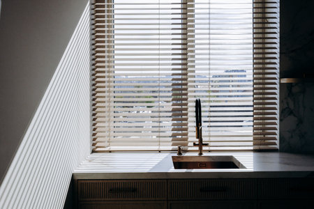 This is a kitchen featuring a sink along with a window that has blindsの写真素材