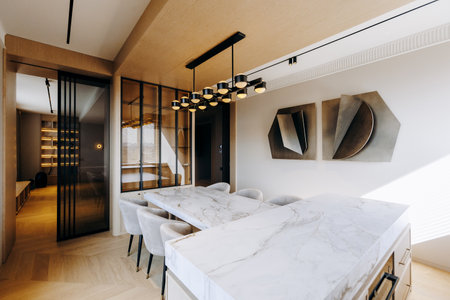 A dining room with a large table, chairs, and a marble countertopの写真素材