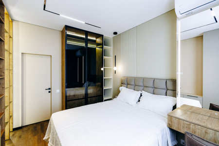 This is a bedroom featuring a large bed positioned alongside a mirrorの写真素材