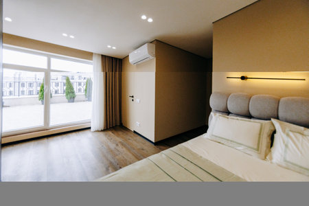 A cozy and inviting bedroom featuring a large bed and an expansive windowの写真素材