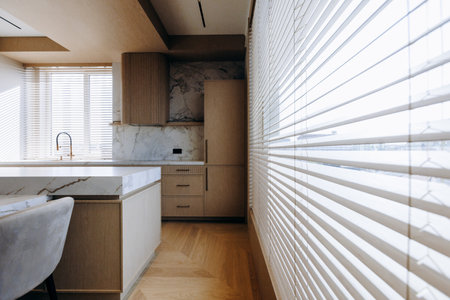 A beautiful kitchen with window blinds and a stunning marble countertopの写真素材