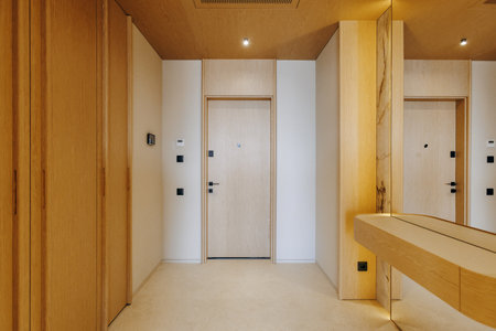 A long hallway featuring a door alongside a mirror mounted on the wallの写真素材