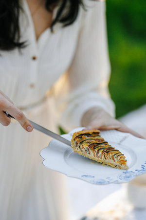 A woman is skillfully cutting a slice of delicious pie on a plateの写真素材