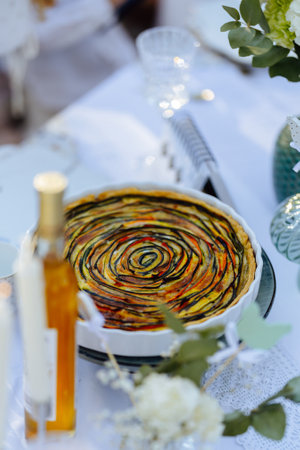 A delicious pie is sitting on a lovely table next to a bottle of wineの写真素材
