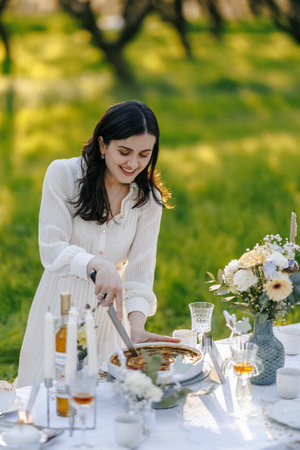 A woman is carefully cutting a delicious piece of cake on a tableの写真素材
