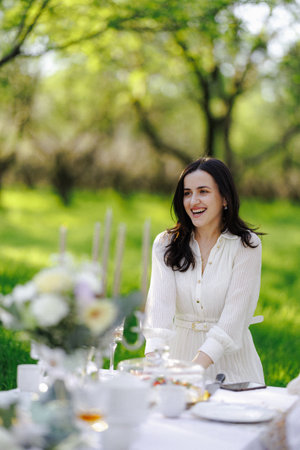 A woman wearing a beautiful white dress is sitting at a tableの写真素材