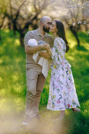 A couple kisses in a park while joyfully holding a babyの写真素材