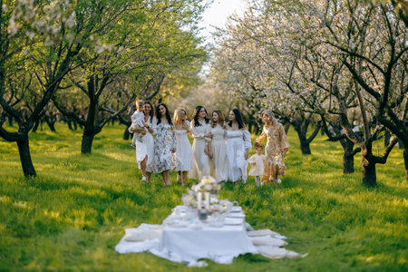 Women in white dresses stand around a table in a parkの写真素材