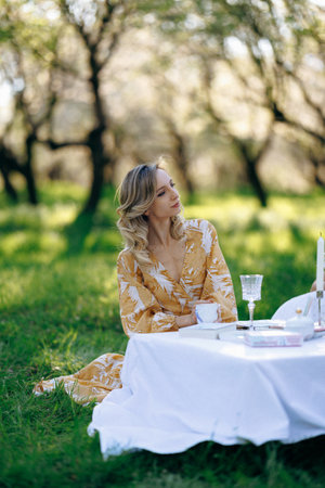 A woman is peacefully sitting at a table placed on the grassの写真素材