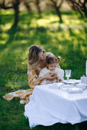 A woman sits at a grass table holding a little girlの写真素材