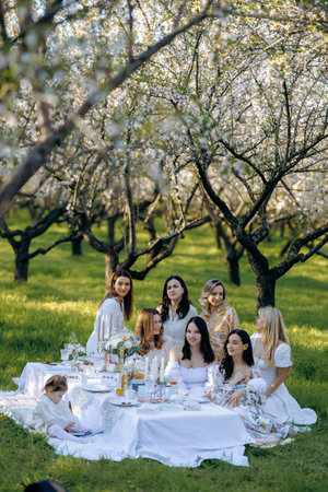 A group of women are happily sitting around a table in a parkの写真素材