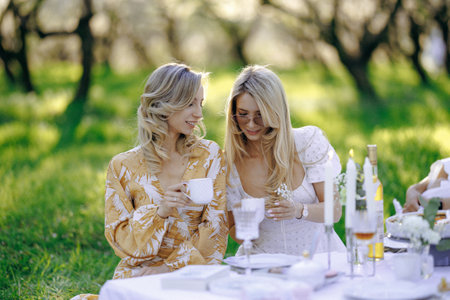 Two women are enjoying tea together at a table on a lovely dayの写真素材
