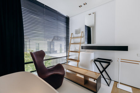 A cozy room with a simple chair and a tall ladder positioned in itの写真素材