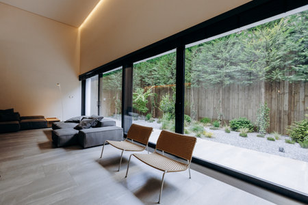 A spacious living room filled with numerous windows and comfortable chairsの写真素材