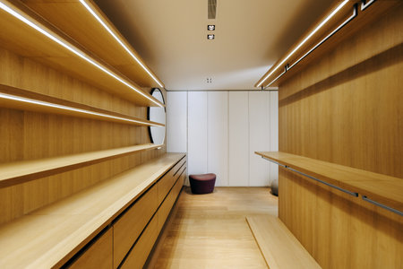 A spacious walkin closet featuring wooden shelves and a large mirrorの写真素材