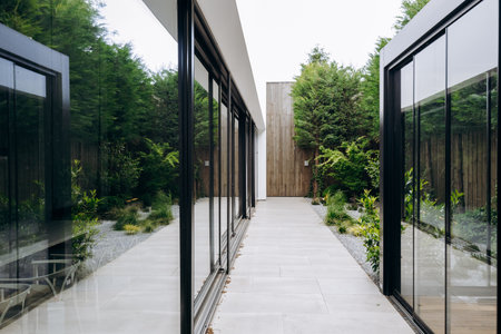 There is a long hallway featuring sliding glass doors that lead to a houseの写真素材