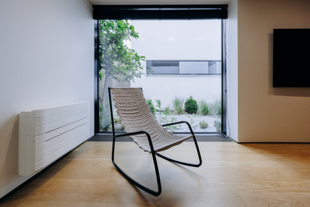 A rocking chair sits in front of a large window in a living roomの写真素材