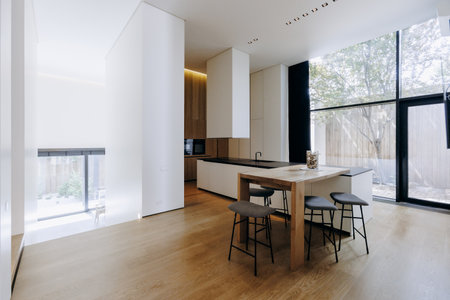There is a kitchen that features a table along with stools placed in itの写真素材