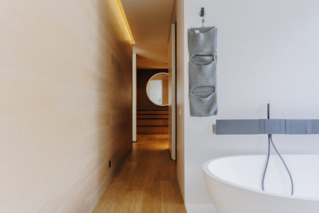 A bathroom featuring a bathtub along with a towel hanging on the wallの写真素材